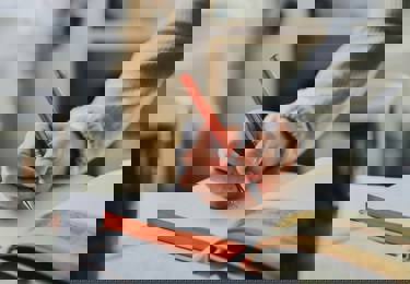 Bild på en student som skriver i en anteckningsbok.